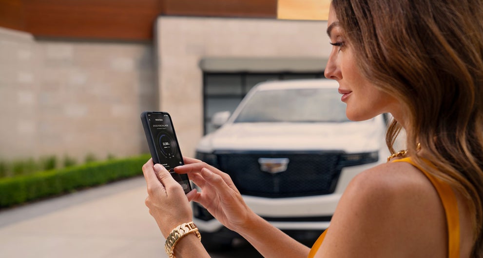lady checking her mobile with a Cadillac vehicle background | Dimmitt Cadillac of Clearwater in Clearwater FL